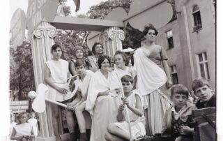 Korowód w latach 60. XX w. Platforma poświęcona antycznej Grecji. Napis głosi: „Greckich bogów rodzina także lubi smak wina”.